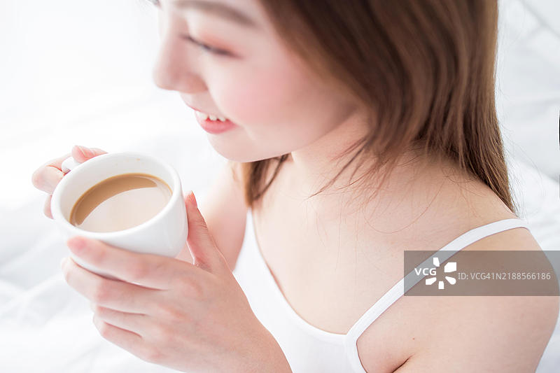 一位女性在床上享受一杯咖啡图片素材