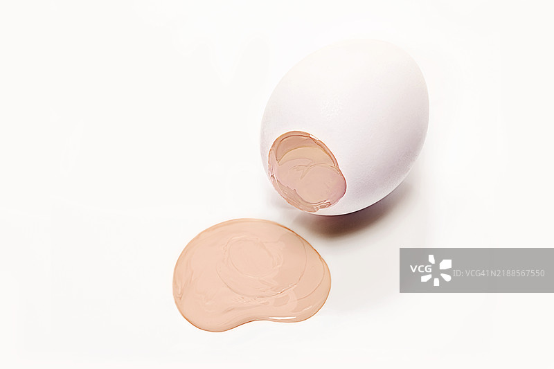美容产品基础化妆品与白色复活节彩蛋的概念。米色颜料流淌在复活节彩蛋上。2025年流行色摩卡慕斯。图片素材