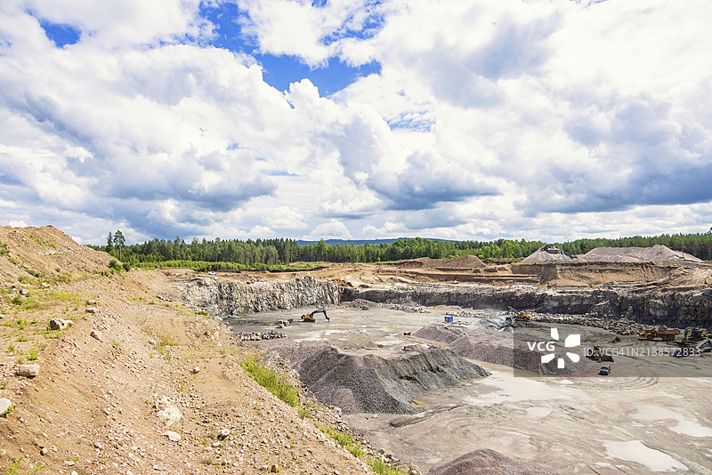 夏季瑞典欧洲森林景观中的活跃采石场，堆满了碎石和机械设备图片素材