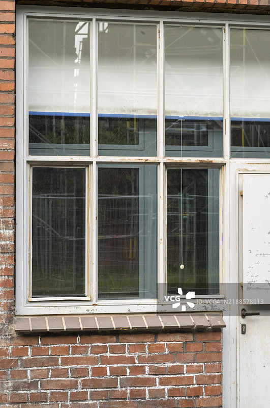 陈旧的窗户和门嵌在砖墙中，显示出岁月的痕迹和磨损，暗示着过去的时代。图片素材