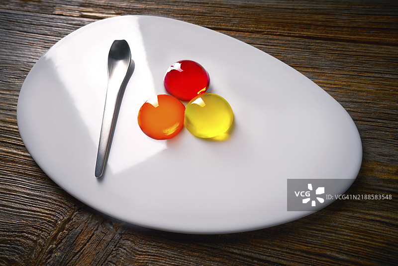 现代椭圆盘中的分子料理概念，色彩丰富的球状物，果冻质感。图片素材