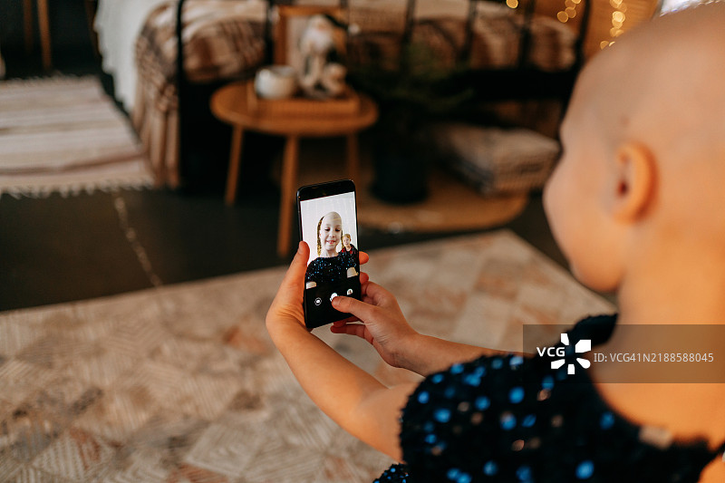 快乐的脱发儿童在她的卧室里自拍图片素材