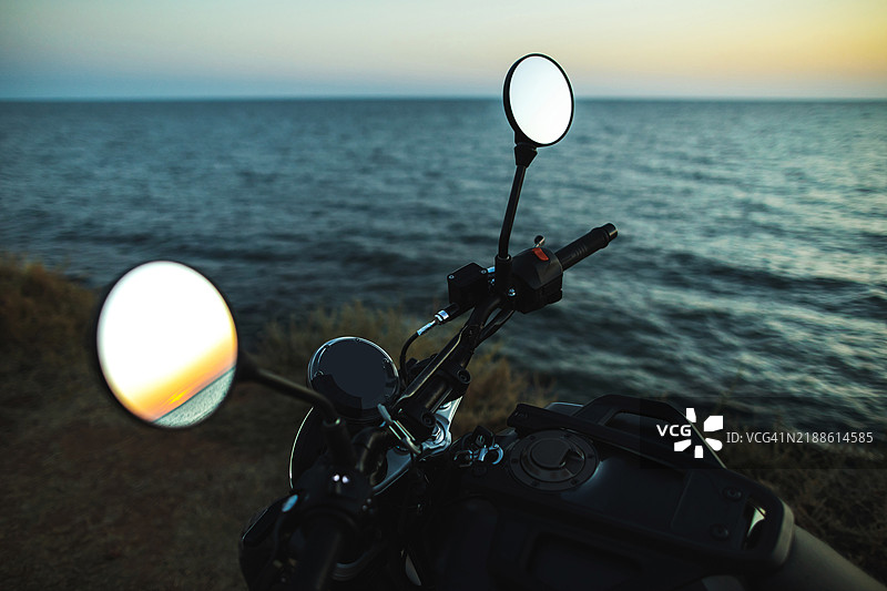 摩托车的特写把手，停靠在海边的日落时分图片素材