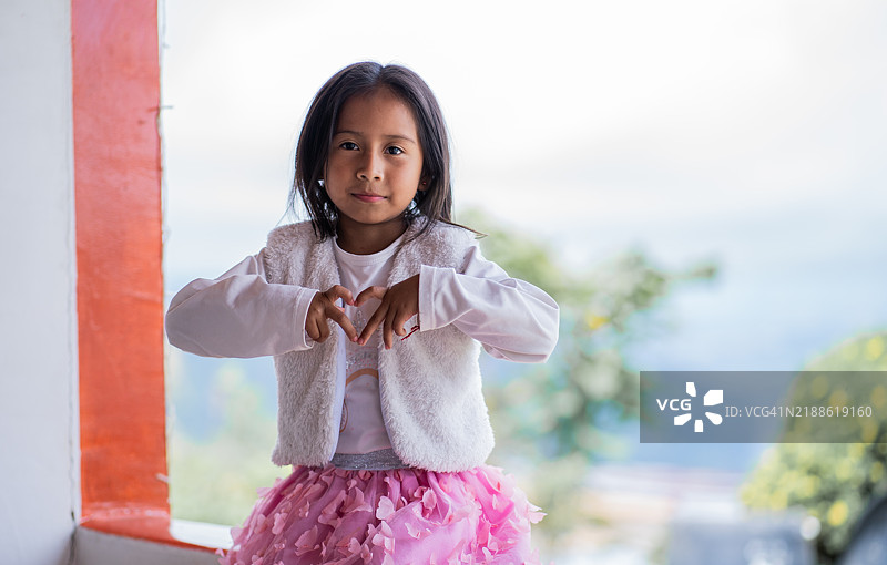 坐着的女孩用手做出心形符号图片素材