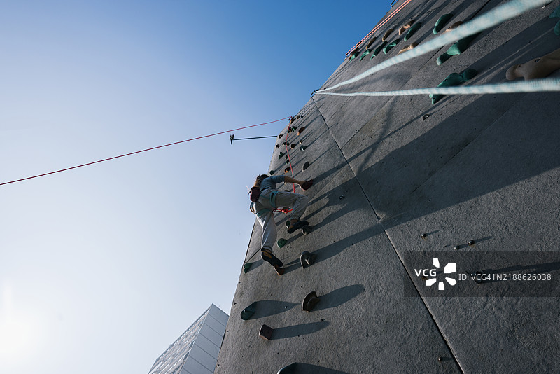 在晴朗的蓝天下攀爬户外岩壁的人图片素材