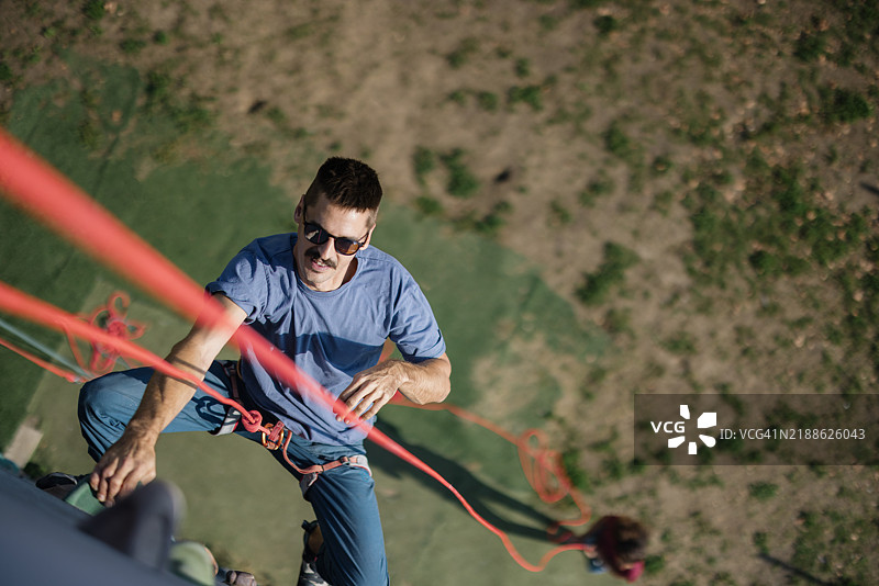 男人攀爬户外岩壁，拥抱积极的冒险生活方式图片素材