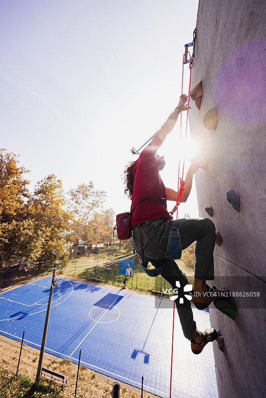 男子在阳光明媚的日子里于体育设施攀爬户外岩壁图片素材