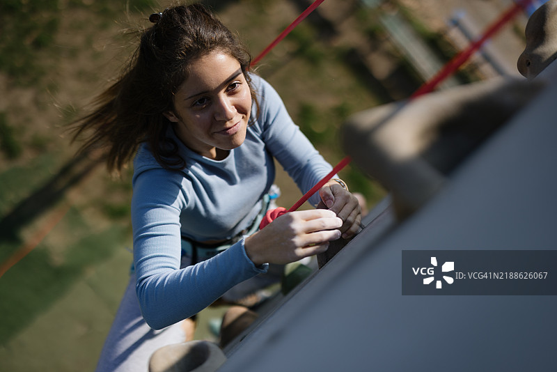 年轻女性攀爬户外岩壁，拥抱积极的生活方式图片素材