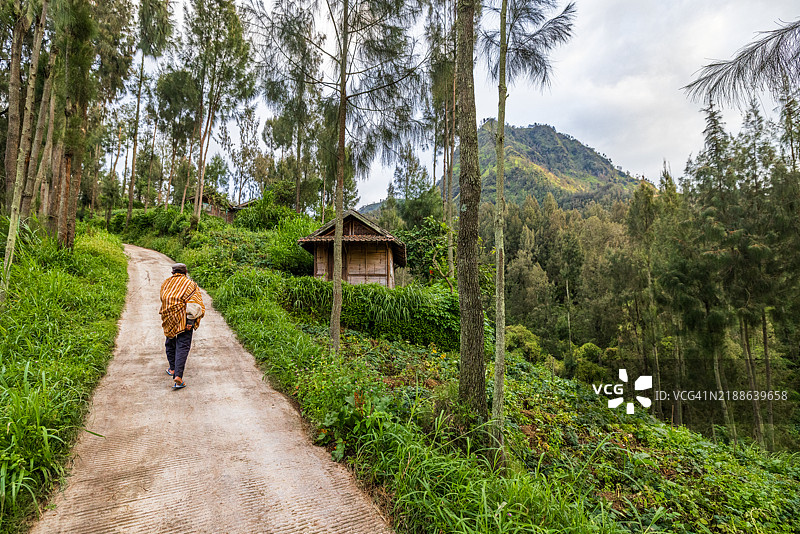 一位农民在布罗莫山脚下的乡村道路上攀爬。图片素材
