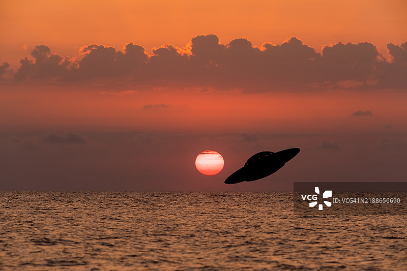 海上日落时的不明飞行物。UFO入侵图片素材