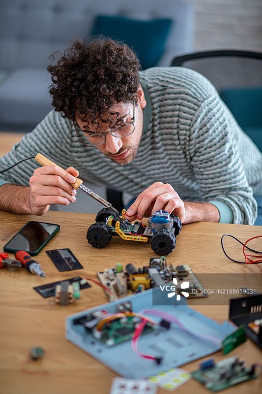 年轻男子正在调整机器人太阳能车的部件图片素材