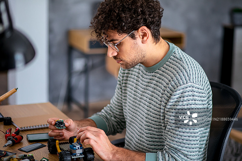 男子正在调整机器人太阳能车的部件图片素材