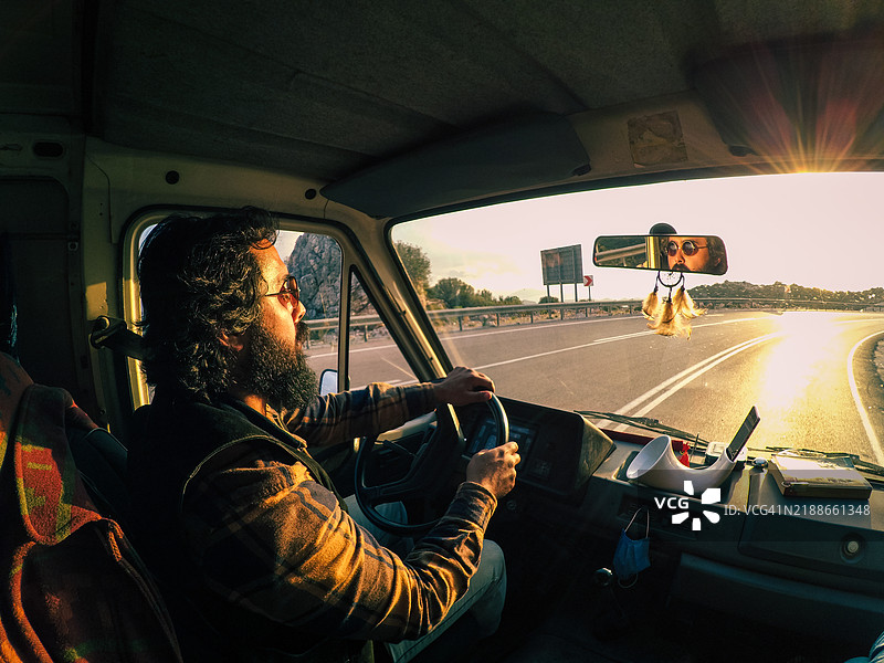 一个嬉皮士带着他的旅行车向西出发，迎着日落。图片素材