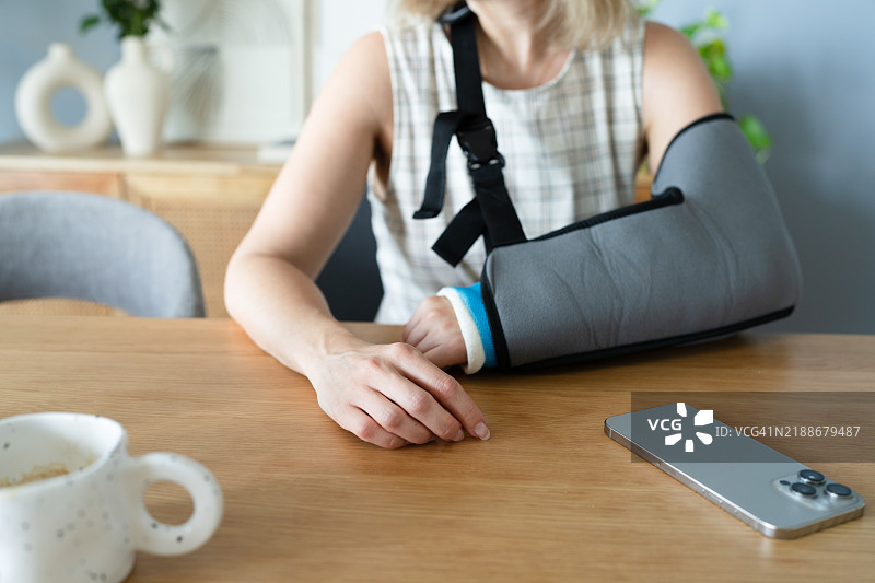 家中手臂骨折的女性与手机图片素材