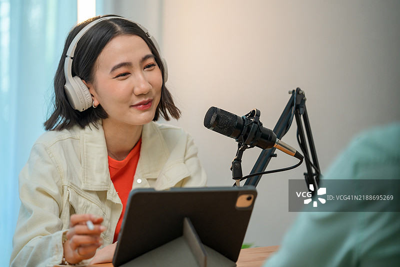 实时互动：一位女性视频博主与嘉宾讨论，分享生活和建议给参与的粉丝，在舒适的空间中进行。图片素材