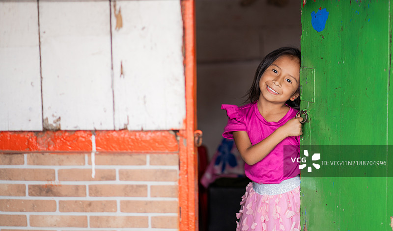 女孩好奇地从家门口朝镜头看。图片素材