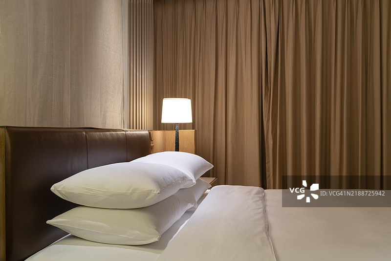 现代酒店中的舒适床铺。图片素材