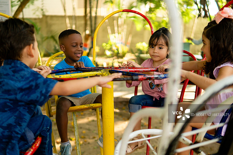 快乐的孩子们在游乐场的旋转木马上旋转图片素材