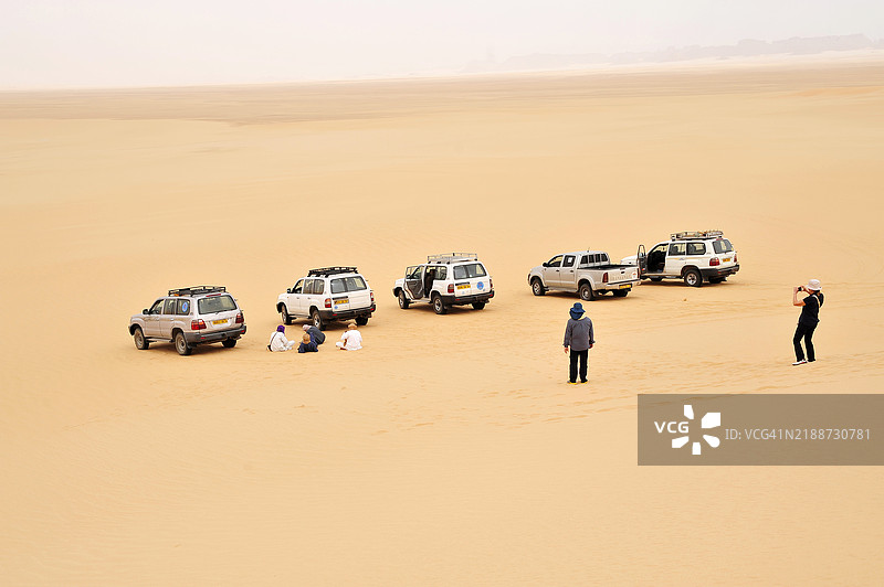 阿尔及利亚 - 经济 - 就业 - 旅游。图阿雷格旅游向导在阿尔及利亚东南部的贾内特绿洲小镇附近的沙漠探险中休息。图片素材