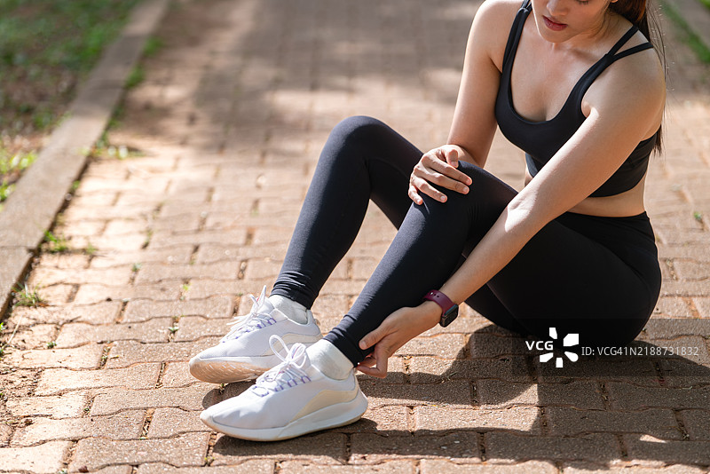 户外跑步时的阿基里斯伤害。女性用手握住阿基里斯腱，特写镜头显示她正在忍受疼痛。运动锻炼中脚踝扭伤意外，跑步慢跑时发生。图片素材