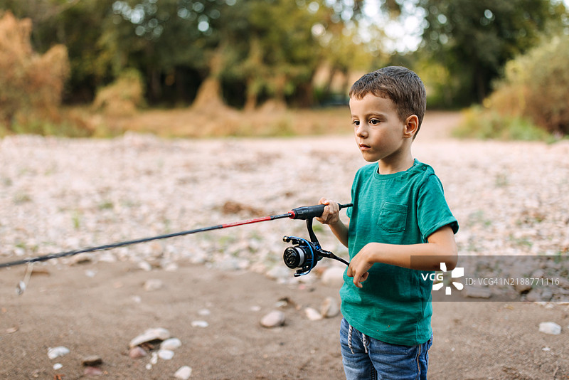 男孩在岸边钓鱼。图片素材