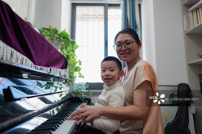 亚洲母亲知道她的儿子在弹钢琴图片素材