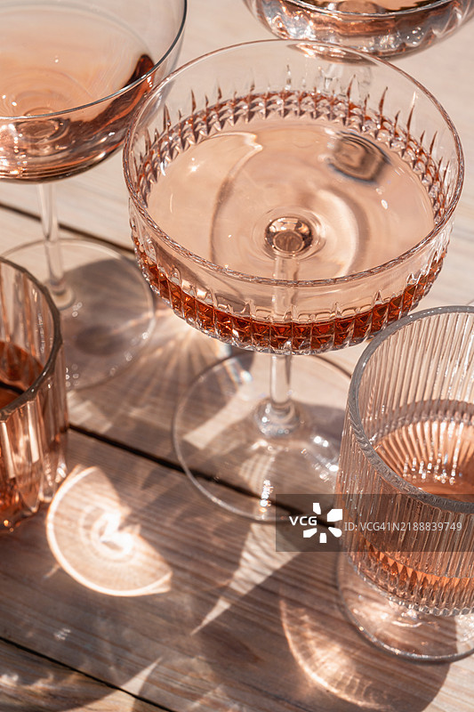 几只装有玫瑰酒的鸡尾酒或无酒精鸡尾酒杯，背景为米色。图片素材