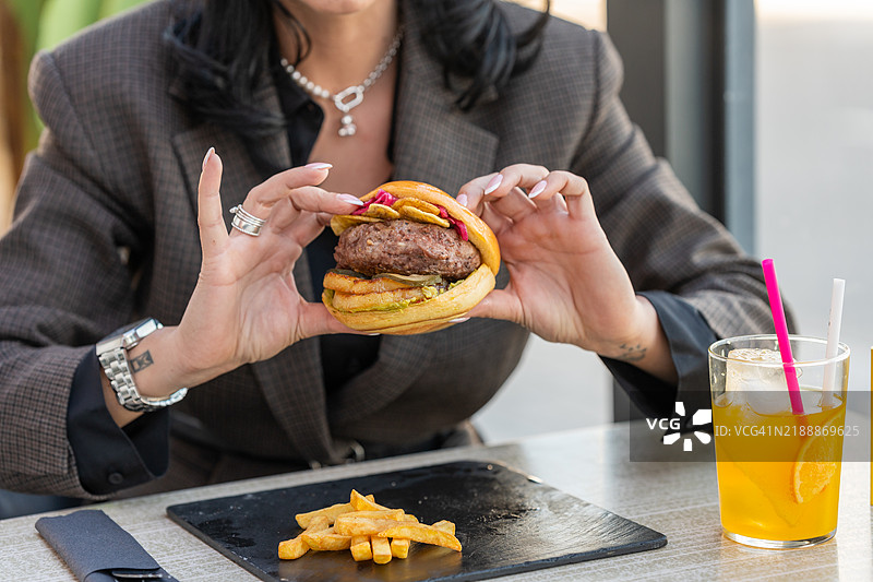 女人在户外餐厅享受美味的汉堡和薯条图片素材
