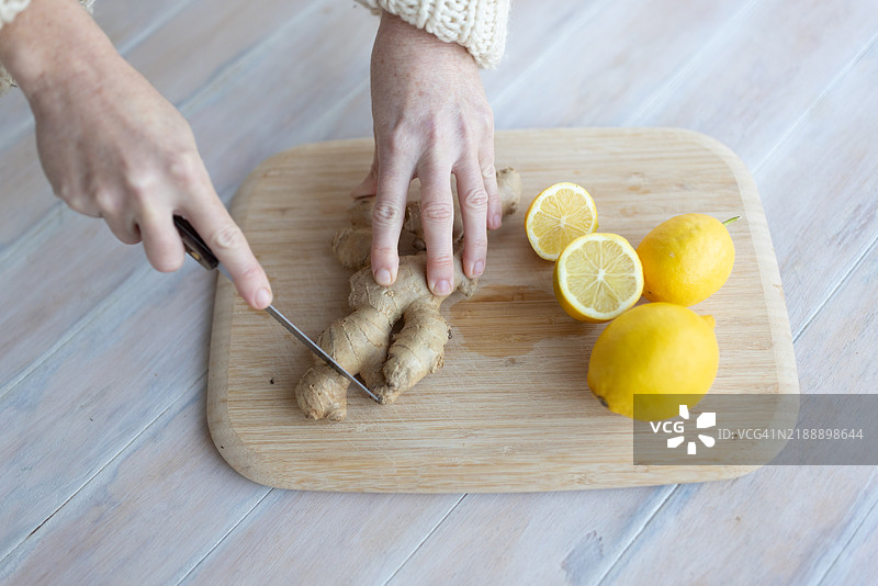 女性手在木砧板上切姜和柠檬 - 库存照片图片素材