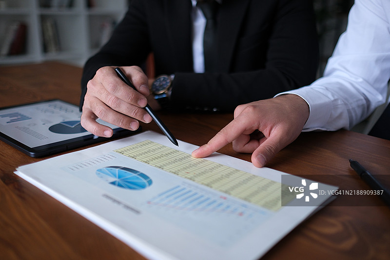 同事们在工作场所分析文件和数字平板上的数据图片素材