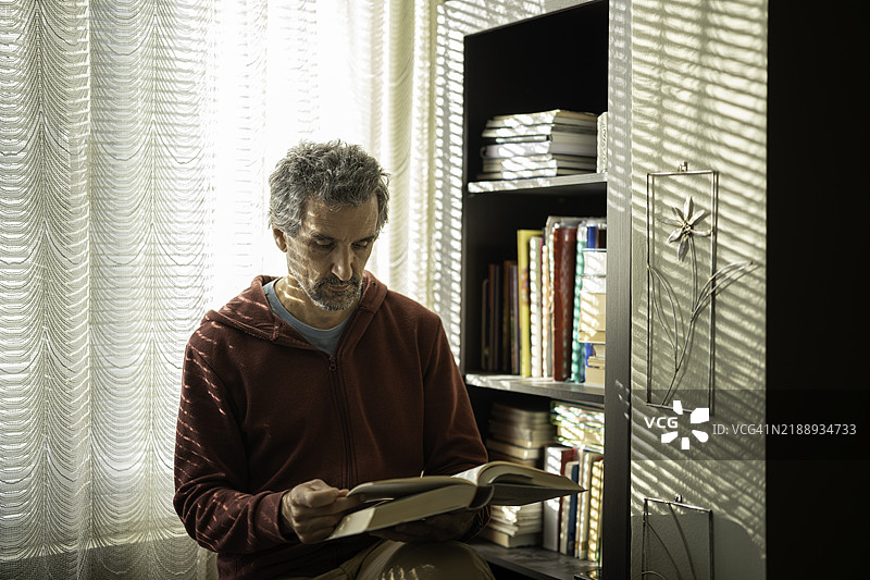 成熟男性在早晨阅读书籍，享受在家放松的时光。图片素材