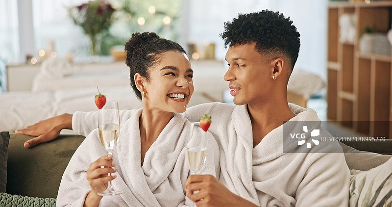 水疗中心，情侣幸福地举着香槟杯，享受奢华、亲密和浪漫的情人节约会。人们在度假村微笑，举杯庆祝，享受饮品，传递关爱、爱意和缓解压力的时光，坐在沙发上。图片素材