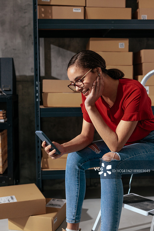 穿着红色衬衫的女人坐着玩手机图片素材