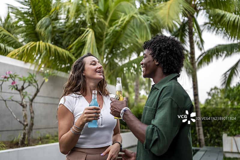 微笑的朋友们在热带户外环境中一起享受饮品图片素材