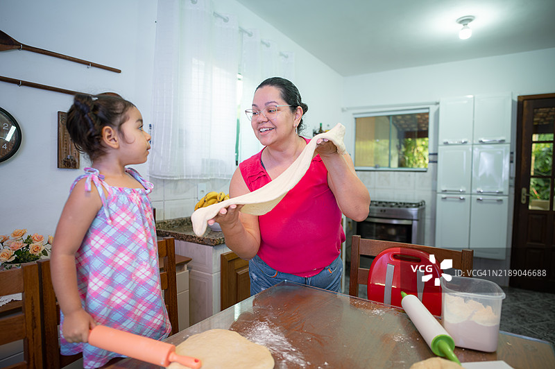 一位母亲在厨房里和她的小女儿一起揉面团。图片素材
