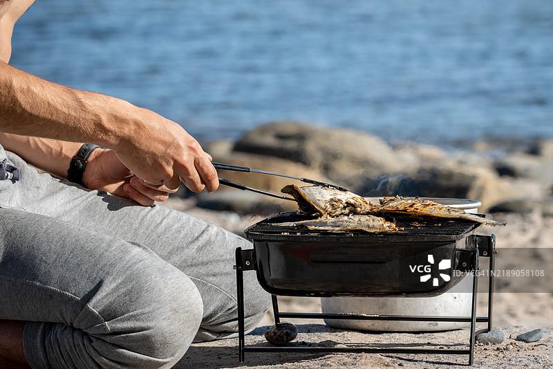 在海边用便携式烧烤架烤鱼图片素材