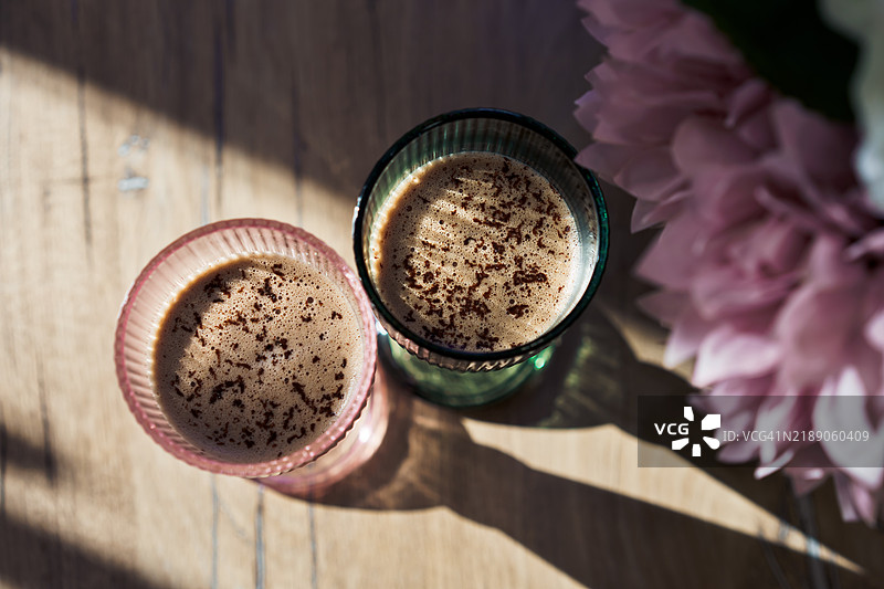 两杯可可饮料与巧克力放在木桌上，俯视图，阳光明媚的日子。图片素材