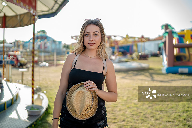 微笑的年轻女性站在发光的旋转木马上图片素材