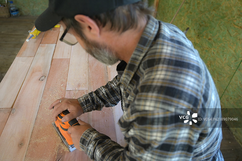 男子在木材上使用圆盘砂光机。图片素材