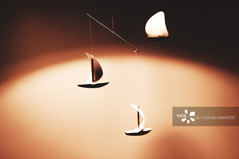 2025年的摩卡色。极简风格的悬挂帆船移动装饰，配有温暖的灯光。图片素材