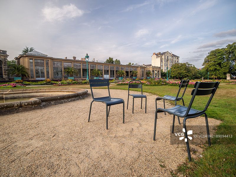 法国雷恩的塔博尔公园法式花园的广角视图，前景有椅子，背景是橘园建筑的外观，位于伊勒-维莱讷省，布列塔尼，法国西部。图片素材