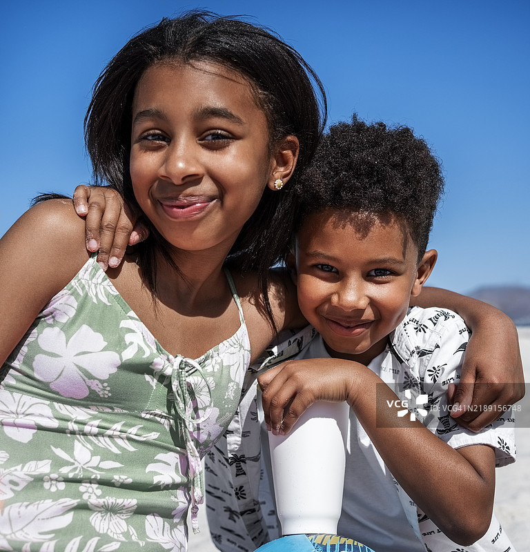 快乐的少女和小弟弟一起享受海滩野餐图片素材
