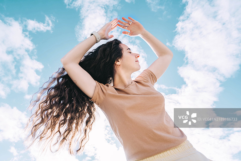 快乐的女性在明亮的蓝天下享受自由图片素材