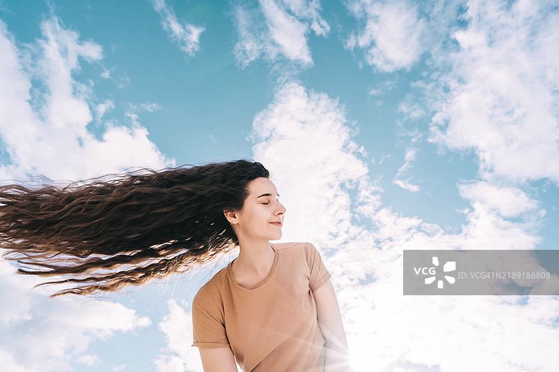 快乐的女性在明亮的蓝天下享受自由图片素材