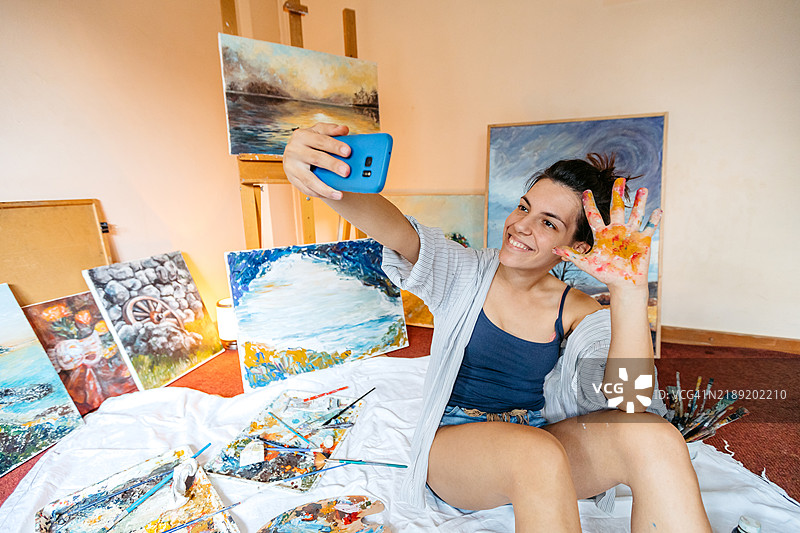 年轻女性艺术家在家里趴在地上拍自拍照，气喘吁吁。图片素材