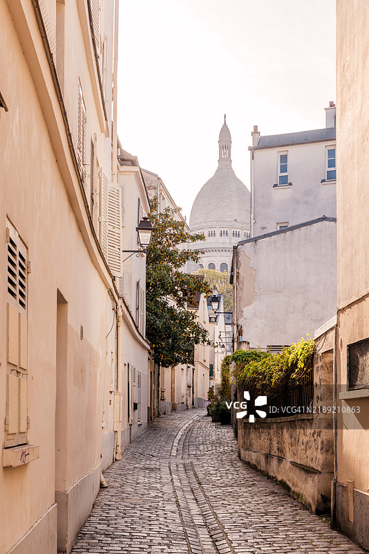巴黎蒙马特区远处的圣心大教堂旁的小巷图片素材