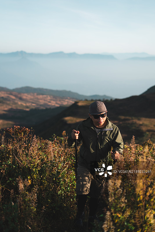 徒步旅行者穿越高地植被，背景是壮丽的山景图片素材