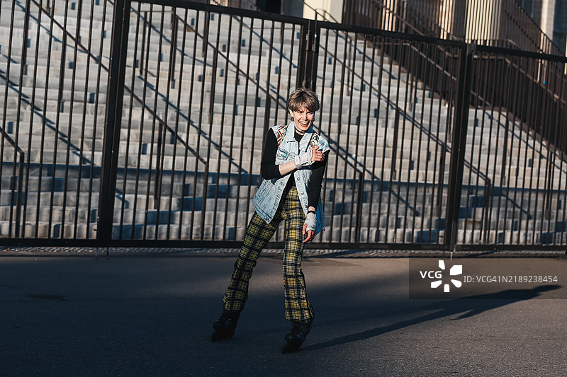 年轻快乐的女性在城市街道上滑旱冰，欢笑玩乐。图片素材