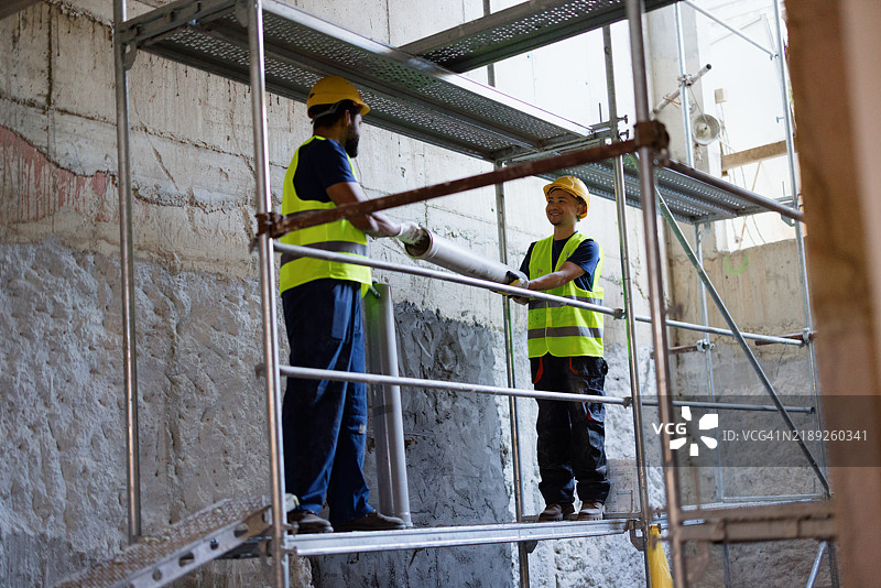 建筑工人在脚手架上合作施工图片素材