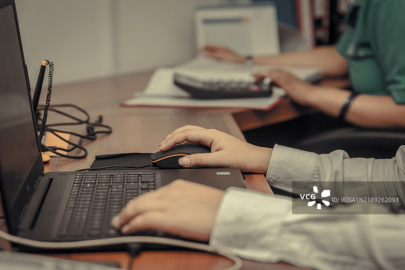 女性坐在桌子上使用笔记本电脑的中部特写图片素材